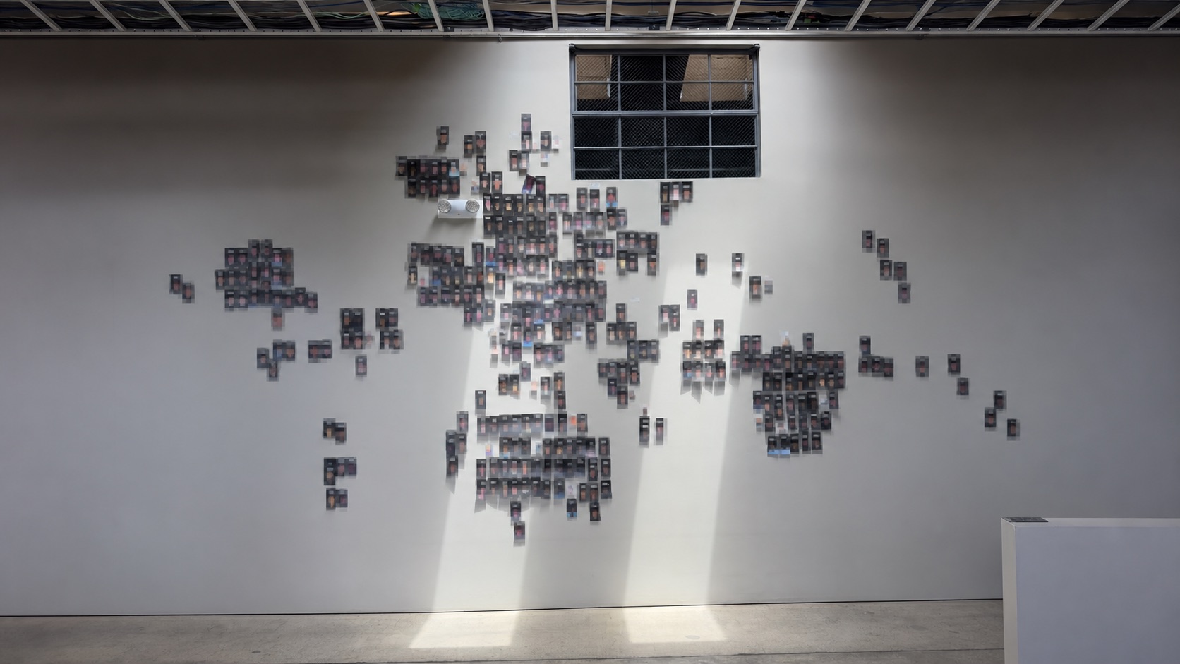 Privacy-protected documentary view of a wall-sized world map assembled from participant records in an international AI study